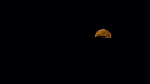 The full moon rises from behind the house. Moon gradually descends Video stock 244057994