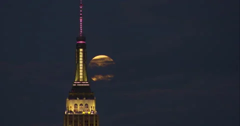 Full moon rises behind top of Empire State Building in cloudy sky Stock Footage 67307582