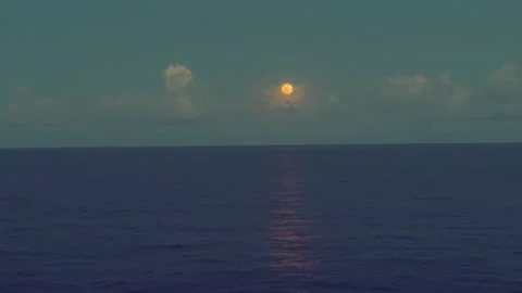 Full moon rises over a calm ocean horizon with clouds softly illuminated in.. Stock Footage 338281700