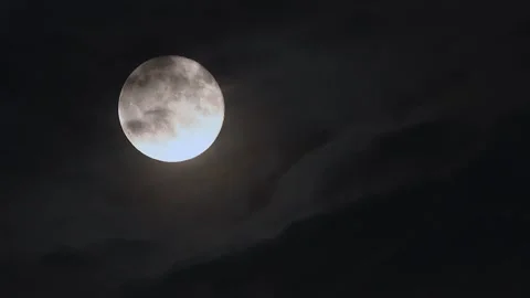 Full moon rises through drifting clouds on a dark night sky in stunning 4k Stock Footage 305429126