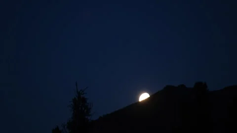 Full moon rising behind mountain ridge at twilight Stock Footage 300991740