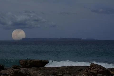 Full moon rising behind small island, Mediterranean sea Stock Photos