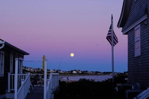 Full moon rising over a Rhode Island beach house with an American flag Stock Photos