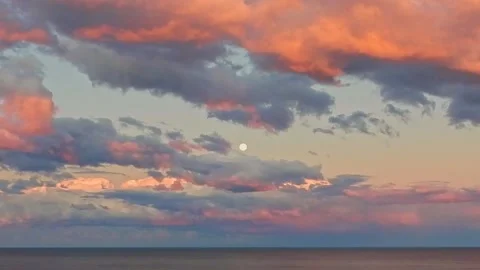 Full moon rising through sunset color clouds Stock Footage 208540090