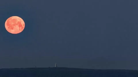 The full moon setting behind the Ailsa Craig &amp; the Lady Isle lighthouse Stock Footage 244167246