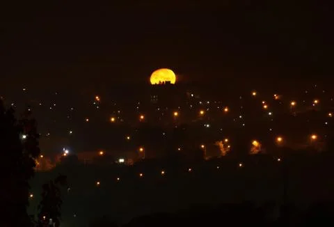 Full Moon Setting over night city. Stock Photos