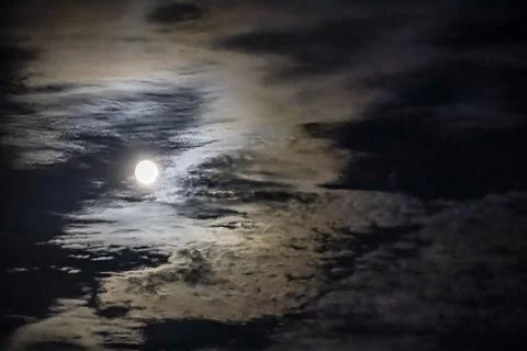Full moon shining brightly through dramatic, wispy clouds at night Foto stock