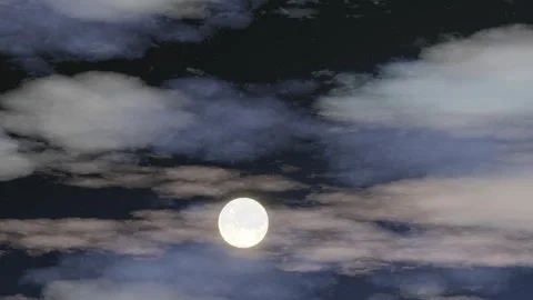 A full moon visible through breaks in the nighttime clouds Stock Footage 261582243