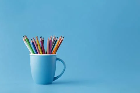 Full mug of sharp color pencils on monochromatic blue background 库存照片