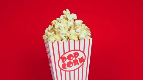Full popcorn in a classic popcorn box on a red background.Popcorn spinning in ci Stock Footage 196685946