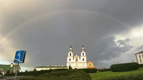 Full rainbow arching over white church with two towers  스톡 동영상 344041590