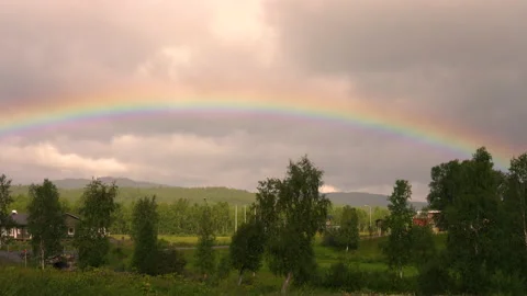 Full rainbow in gloomy cloudy sky in Lapland's mountains, panning video Stock Footage 219427750