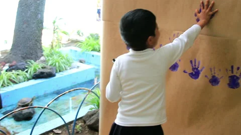 FULL SHOT. Child put his hands painted in a wall in the kindergarten. Stock Footage 48440860