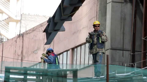 FULL SHOT. Construction worker is directing the movement of a big metal piece. Stock Footage 41122324