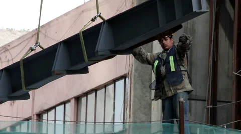 FULL SHOT. Construction worker is directing the movement of a big metal piece. Stock Footage 41126133