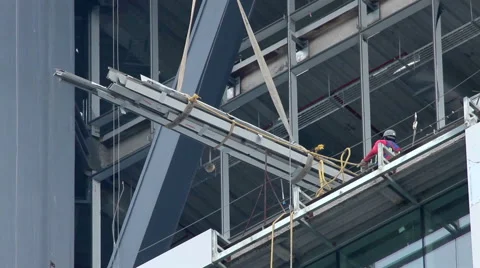 FULL SHOT. Construction worker is directing the movement of a big metal piece. Stock Footage 41129267