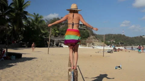 FULL SHOT. Girl using her balance in a slackline in the beach. Stock Footage 49761877