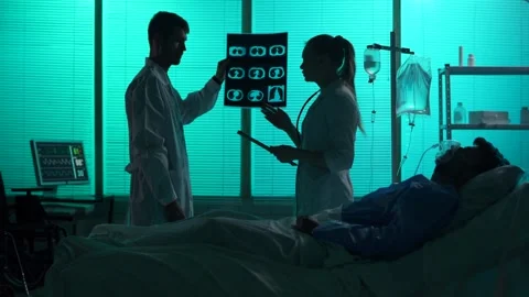 Full-sized silhouette video of two doctors standing behind a patient on a Stock Footage 251895542