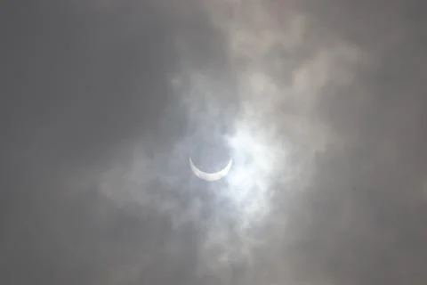 Full Solar Eclipse seen in the cloudy sky. Stock Photos