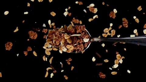 A Full Spoon Of Cereals falling down on black background closeup in super slow Video stock 121431707