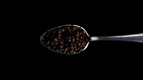 A Full Spoon Of falling peppercorns down on black background super slow mo Stock Footage 121430656