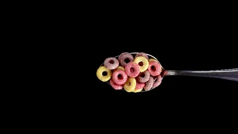 A Full Spoon Of froot loops Flying up and Falling down on black background Stock Footage 121428875