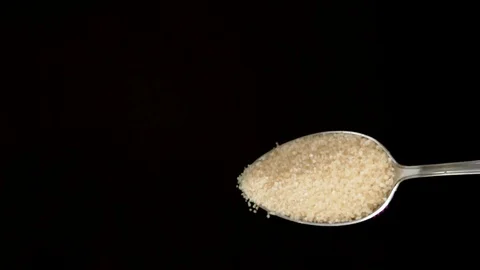 A Full Spoon of sugar Flying up and Falling down on black background slow mo Stock Footage 121429626