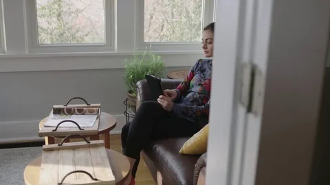 Full tracking shot of a pretty young lady working on a tablet in a sunroom Stock Footage 70808847