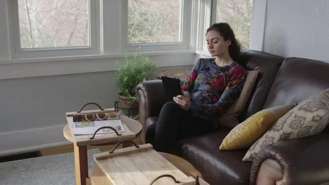 Full tracking shot of a young lady working on a tablet in a sunroom Stock Footage 70808750