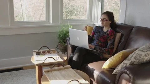 Full tracking shot of a young lady drinking coffee and working on laptop Stock Footage 70809604