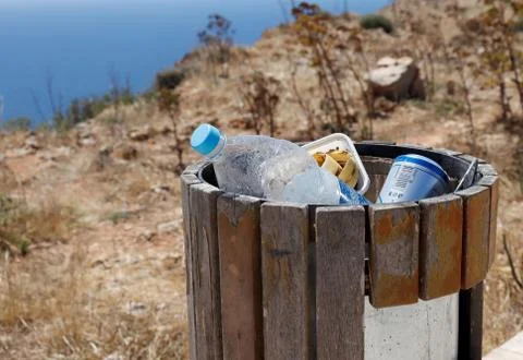 Full trash or litter bin with pet bottle, beer can and organic waste visibile 库存照片