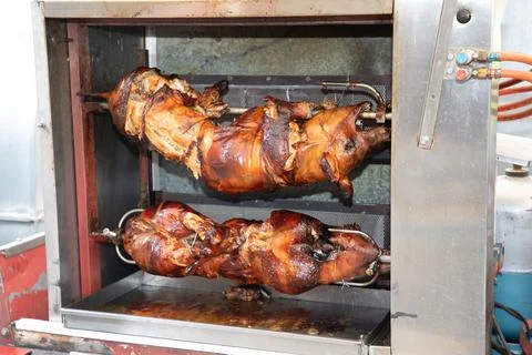 Full two fried piglets pig and lambs on skewers of fire mobile rotisserie Stock Photos