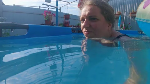 A full woman's face swimming in the pool among children's inflatable laps Stock Footage 201645127