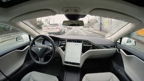 Fully-autonomous self-driving Tesla vehicle navigating a hectic urban landscape Stock Footage