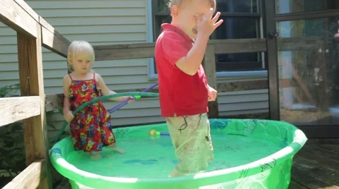 Fully clothed boy laughs and points while in kiddie pool Stock Footage 40027956