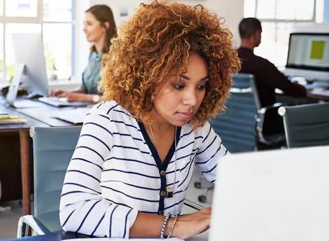 Fully engaged in her work tasks. a young woman using a computer at her desk in a Foto stock