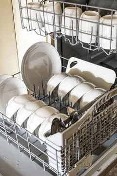 Fully loaded open dishwasher with clean white dishes, bowls and mugs Stock Photos