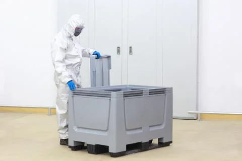 Fully protected technician at large plastic container checking contents Stock Photos