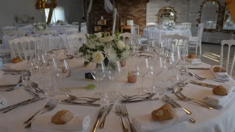 Fully set round wedding table beneath warm string lights, rising view Stock Footage 348196107