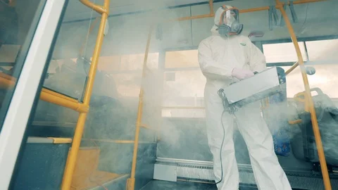 Fumigation of a bus interior done by a specialist in a hazmat suit. Disinfection Video stock 128987239