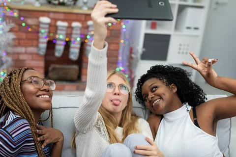 A fun and collaborative selfie in front of a fireplace decorated for Christmas. Stock-Fotos