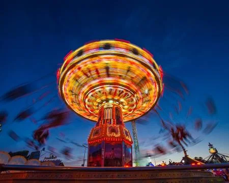 Fun at the chain carousel with people rotating in the evening hour Stock Photos
