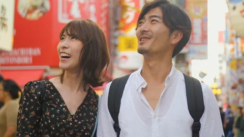 Fun classy Japanese couple explore Osaka food street bright lights background Vídeo Stock 111401856