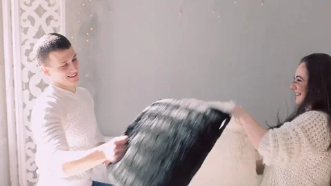 Fun couple resting affectionately after a pillow fight Stockbeeldmateriaal 74025723