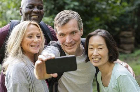 Fun diverse group of middle-aged friends taking a selfie in public park Stock Photos