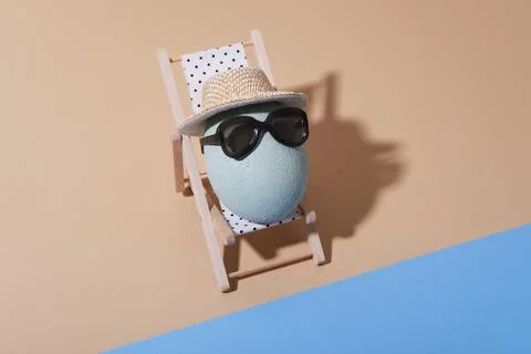 A fun Easter concept for traveling with an egg on a sun lounger on the beach  库存照片