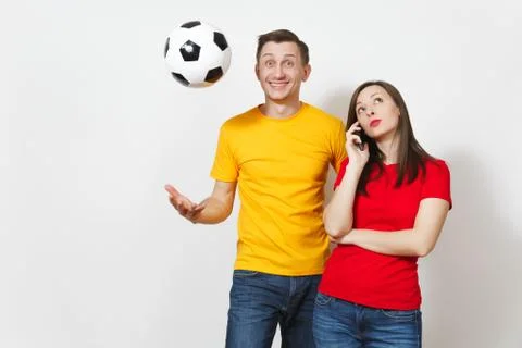 Fun engaged young man, indifferent woman talking on mobile phone, football fa Stock Photos