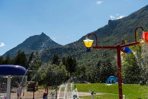 Fun-filled day at the splash pad with mountain views and blue sky above. Stock Photos