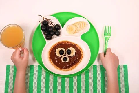 Fun food for kids. pancakes with grapes and banana in a rabbit-shaped plate Stock Photos
