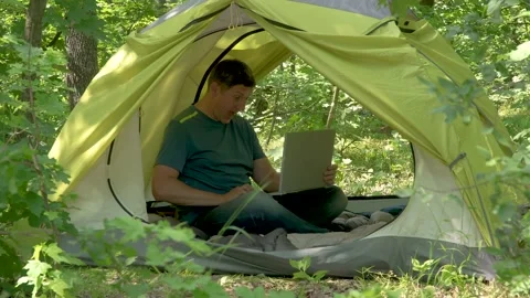 Fun freelancer with laptop in a tent in the forest Stock Footage 134510098